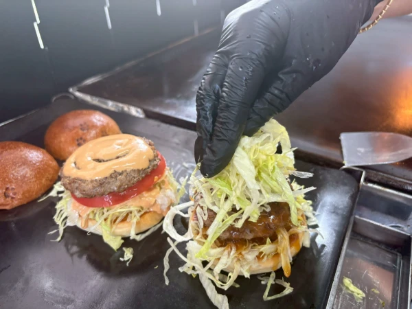 鉄板でハンバーガーを仕上げる手元
